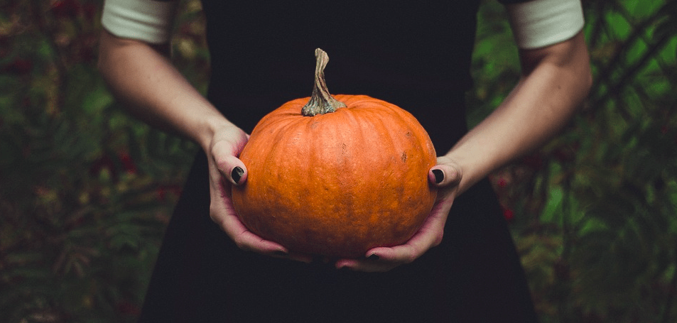 A girl holding a pumpkin.